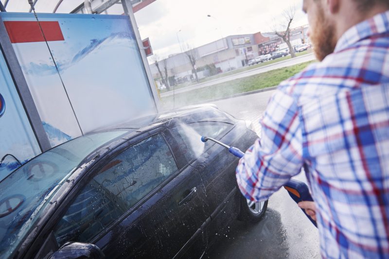férfi magasnyomású mosóval mossa az autót